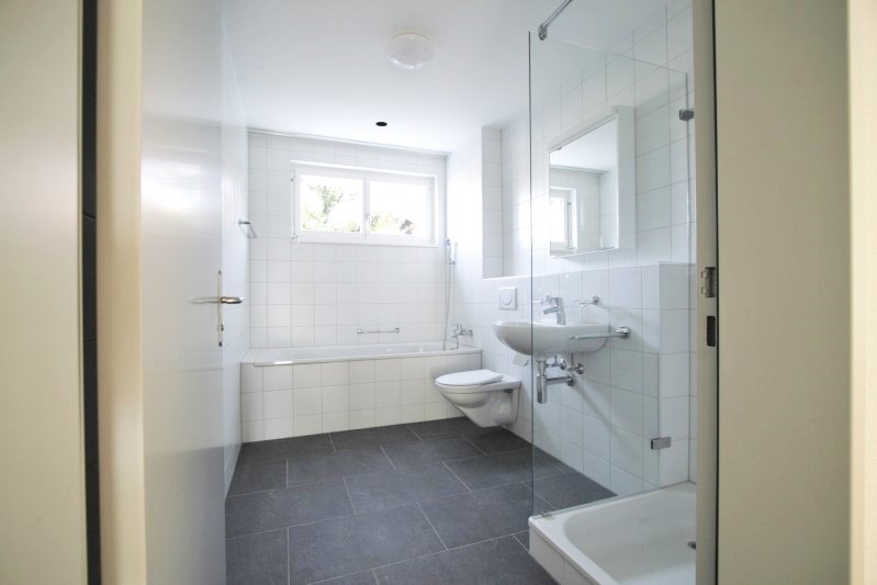 Grosses Badezimmer mit Badewanne und Dusche im Solar Mehrfamilienhaus